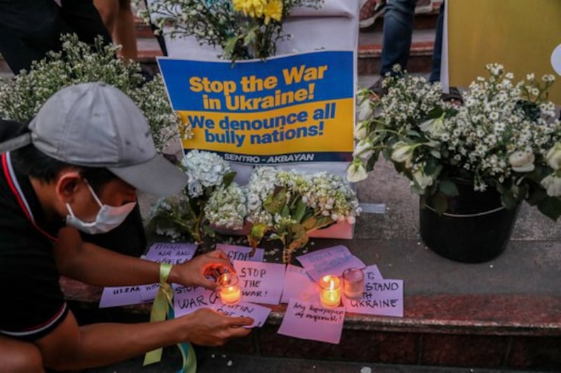 A Filipino activist lights candles during a rally in Quezon City, near Manila, to protest against Russia's invasion of Ukraine, Feb. 28, 2022. Credit: Basilio Sepe