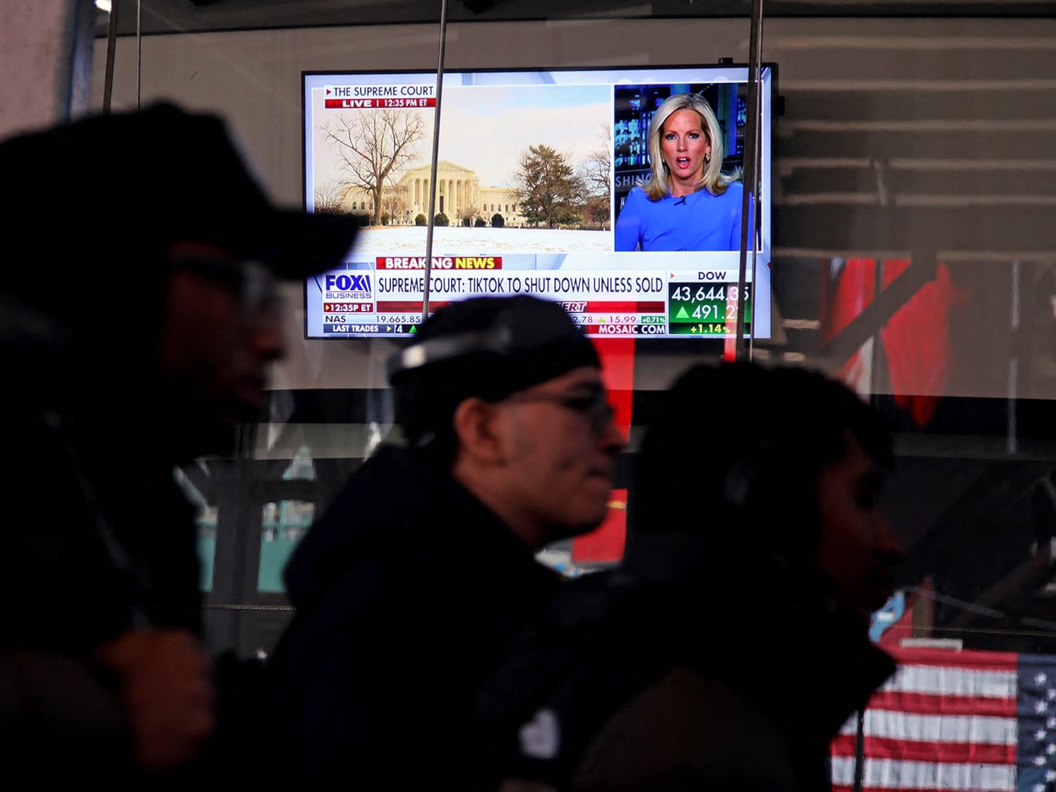 Menschen gehen am 17. Januar 2025 in der Nähe des Times Square in New York City an einem Fernseher vorbei, auf dem eine Nachrichtensendung über TikTok läuft.