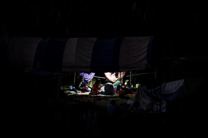 Refugees, who have fled a flare-up in fighting between the Myanmar army and insurgent groups and settled temporarily on the Moei River Bank, eat under a makeshift tent on the Thai-Myanmar border, in Mae Sot, Thailand, Jan. 7, 2022. REUTERS/Athit Perawongmetha