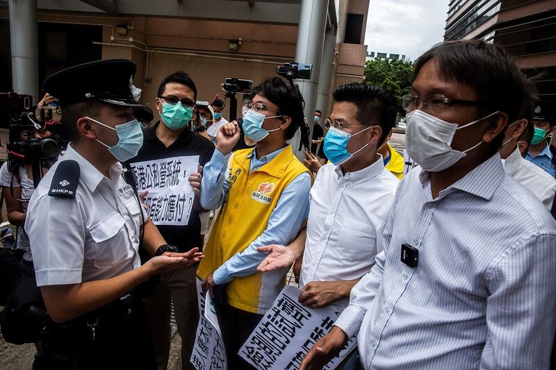 2020年8月2日，香港民主派文员呂文光 （中）在香港医管局外面抗议中，与警官谈话，反对中国协助在港进行武汉肺炎全民普筛。（AFP） 