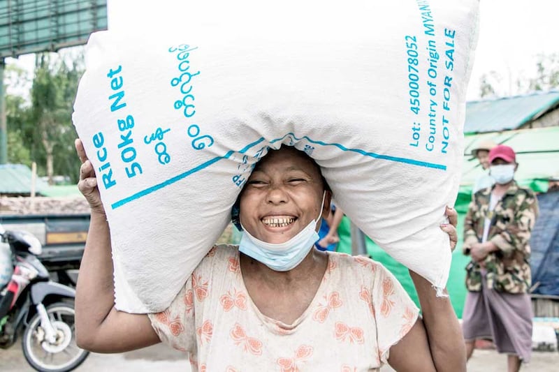 A woman smiles after receiving a bag of rice from the World Food Programme. WFP says it is increasing the number of people it assists in Myanmar from 1.3 million to 3.3 million. (AFP)