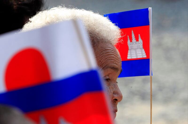 A file photo showing a Cambodian Buddhist nun framed by Japan's flag and her national flag as she listens to Prime Minister Hun Sen during an inauguration ceremony of a road funded by Japan outside of Phnom Penh, Cambodia, March 13, 2018. Credit: AP