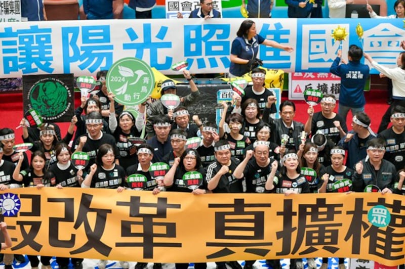 Lawmakers (bottom) from Taiwan's ruling Democratic Progressive Party display a banner reading 'False reform, true expansion of power,' as main opposition Kuomintang legislators unveil a banner reading 'Let sunshine light into Parliament' while voting for a controversial reform bill in Taipei, May 28, 2024. (Sam Yeh/AFP)