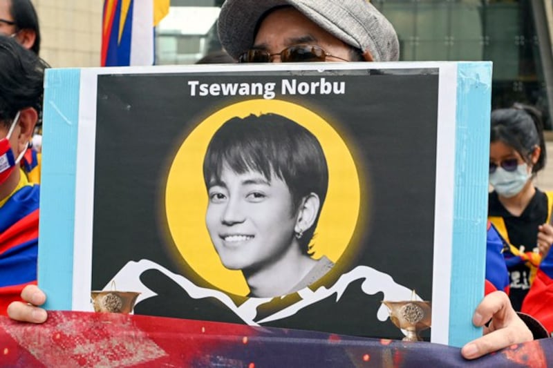 An activist holds a placard showing a portrait of late Tibetan singer Tsewang Norbu, who, according to Tibetan rights groups, self-immolated during a protest in Lhasa, capital of western China's Tibet Autonomous Region, on Feb. 25, 2024. (Sam Yeh/AFP)