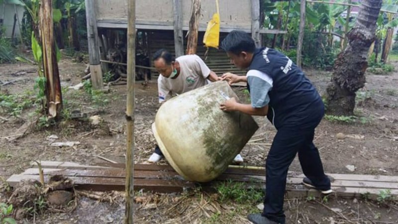 Lao health workers empty stagnant water from a large outdoor container to prevent mosquitoes from laying eggs in the Vientiane capital region in an undated photo.