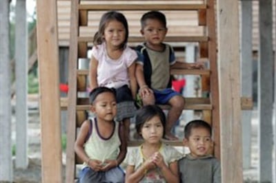 Children sit on the stairs of a house at the Sop On resettlement village in Laos' Nakai plateau, June 28, 2007.