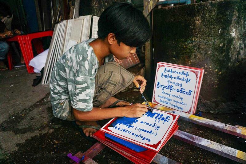 A young worker removes unwanted paint from a marble plate engraved with the names of donors and a dedication. (Myo Min Soe/RFA)