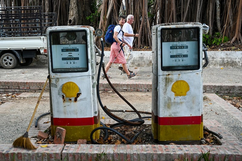 Tourists walk past an abandoned gas station in Luang Prabang on Jan. 31, 2024. (Tang Chhin Sothy/AFP)