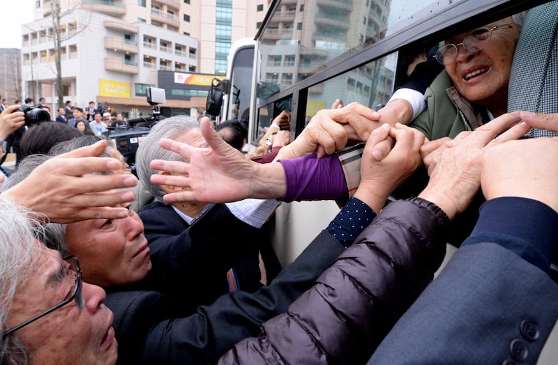 North Koreans (in the bus) grip hands of their South Korean relatives as they bid farewell after a separated family reunion meeting at the Mount Kumgang resort on the North's southeastern coast on October 22, 2015.    North and South Korean families divided by war for more than 60 years said a final, traumatic farewell on October 22 after a reunion event that, for most, marked the last time they will ever see each other.  REPUBLIC OF KOREA OUT    AFP PHOTO / POOL / The Korea Press Photographers Association (Photo by KPPA / POOL / AFP)