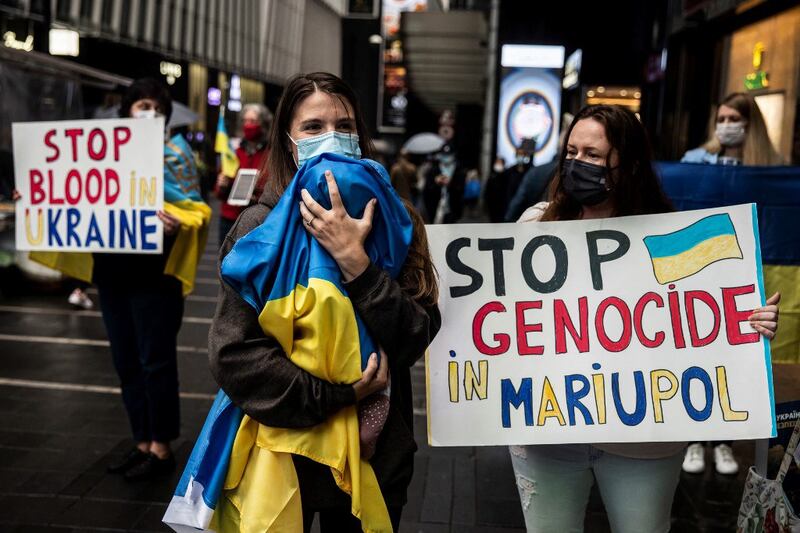 A women (C) holds her baby in a Ukrainian flag as people protest to mark the one-month mark of Russia's invasion of Ukraine, on a street in Hong Kong, March 24, 2022. Credit: AFP