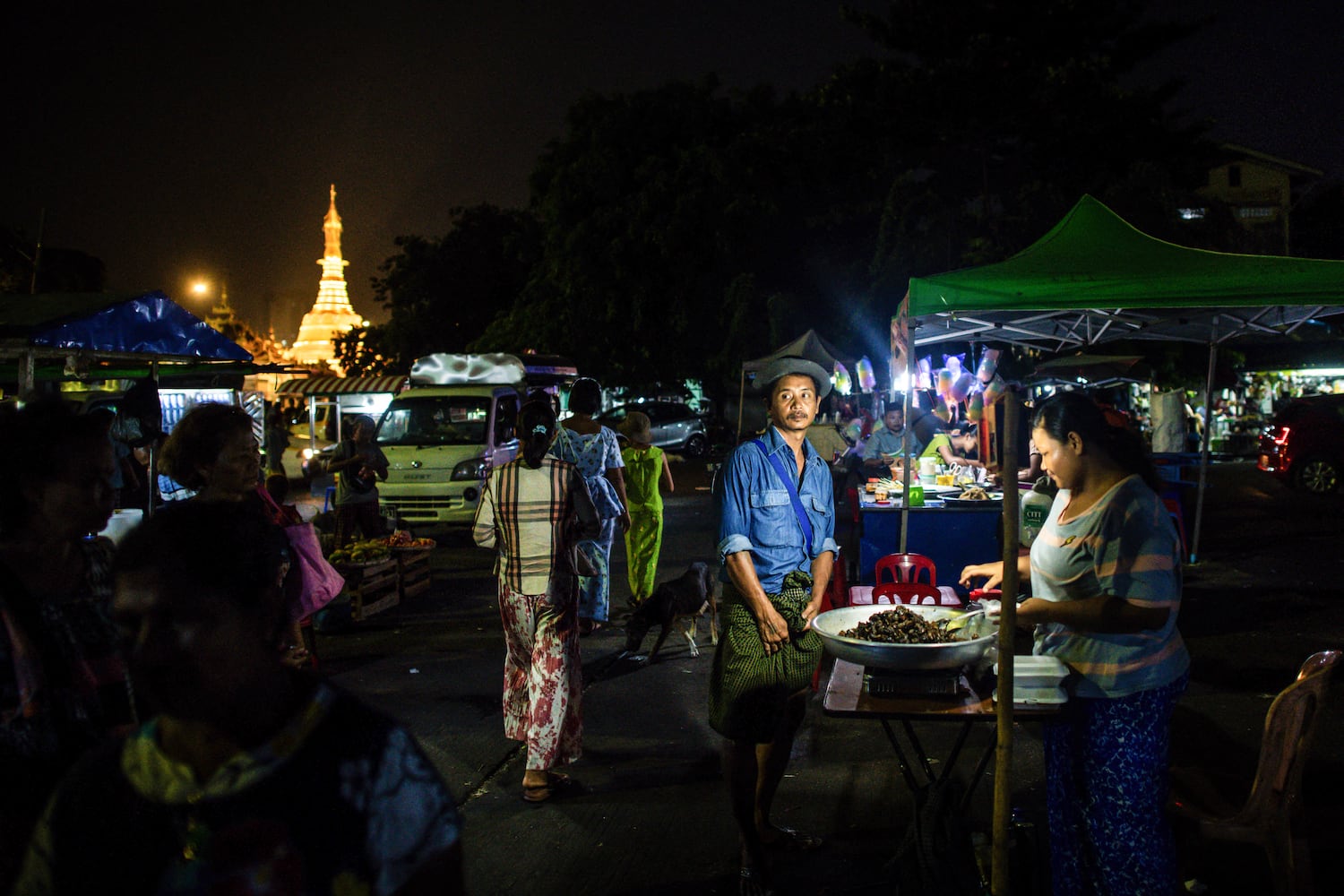 Eine Verkäuferin verkauft während eines Stromausfalls in Yangon am 26. April 2024 von ihrem Stand aus Lebensmittel an einen Kunden.