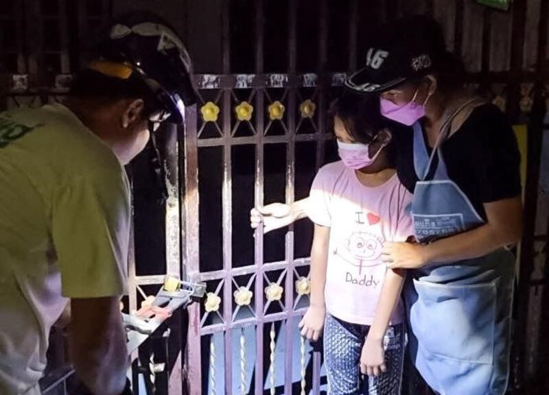 Jiraporn Thepabutra and her 8-year-old daughter wait for an activist to cut the lock after debt collectors put super glue in the keyhole at her home in Bangkok, July 29, 2022. Credit: Handout photo courtesy of Eakpob Laungprasert