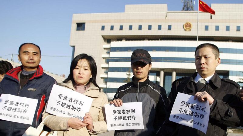 2008 年 12 月 31 日，河北省石家庄市法院外，一群被害人家属举着“受害者权利，不能被剥夺”的横幅，三鹿集团前负责人田文华受审。（法新社）