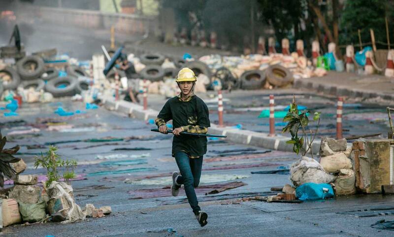 A protester carrying a sword runs along a Yangon street on Tuesday. AFP photo