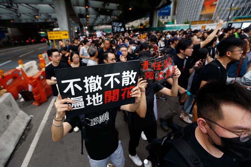 2019年7月7日，香港反送中大游行，示威者手持标语牌“不撤不散 遍地开花”。（美联社）