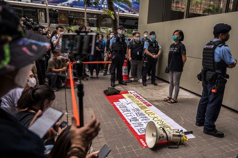 Chan Po-ying (2nd R) of the League of Social Democrats waits as police question two of her colleagues before they hold a protest against the selection process of the city's chief executive in Hong Kong , May 8, 2022. Credit: RFA.