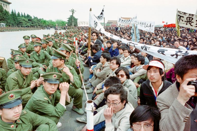 1989年4月22日，前共产党领导人、自由派改革家胡耀邦葬礼当天，支持民主的学生抗议者在未经授权的情况下，与警察面对面坐在在天安门广场的人民大会堂外悼念胡耀邦。（亨丽埃特/法新社）