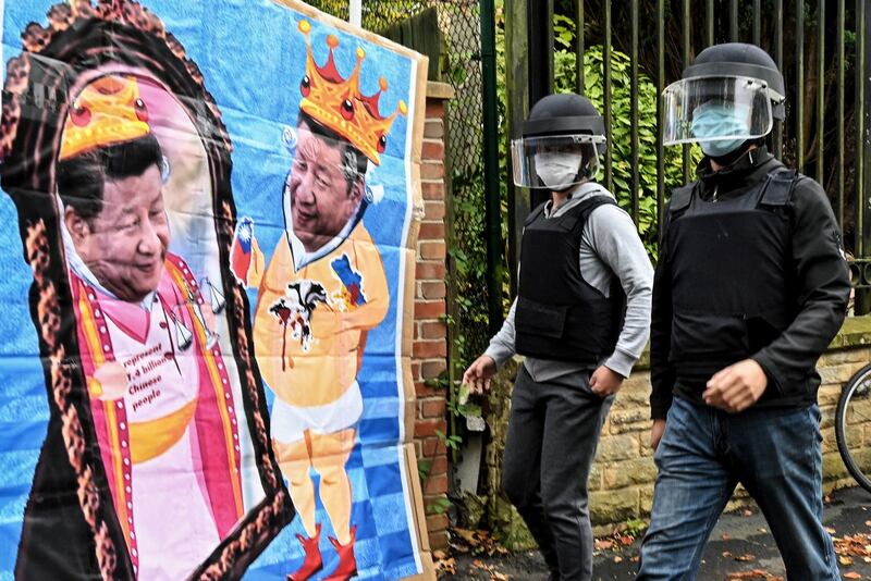 Staff from the Chinese consulate walking toward a poster featuring images of China's President Xi Jinping to remove it during a demonstration by pro-democracy protesters outside the consulate in Manchester, United Kingdom, Oct. 16, 2022. Credit: Matthew Leung/The Chaser News/AFP