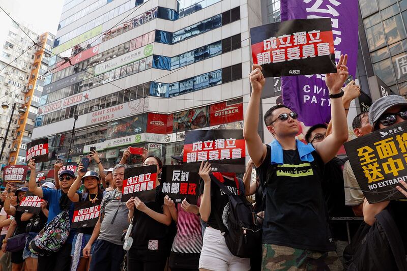 资料图片：2019年7月21日，香港反送中大游行时，示威者举着标语“成立独立调查委员会”。（美联社）