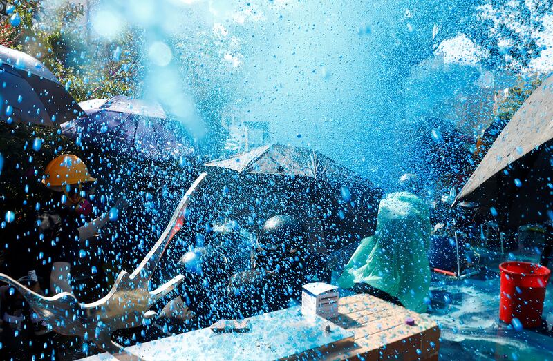 Protesters are sprayed with blue liquid from a water cannon during clashes with police outside Hong Kong Polytechnic University in Hong Kong, Nov. 17, 2019.