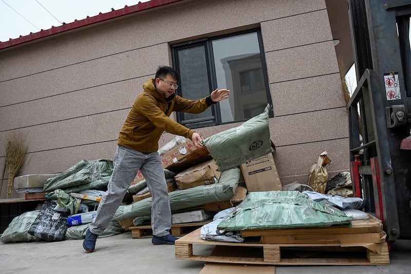 A man transfers packages containing wedding photos, sent from clients to be shredded, onto a forklift in Langfang, in northern China's Hebei province, March 27, 2024.