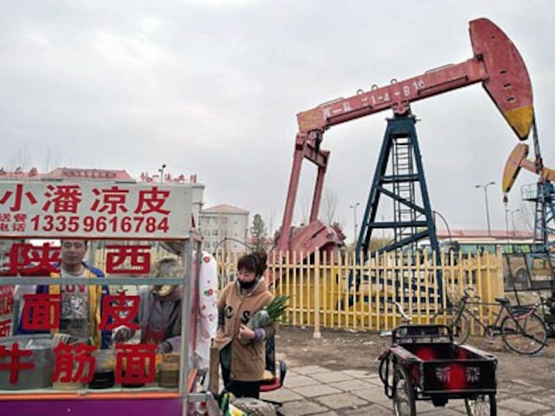 A local resident buys noodle soup from a cart next to an oil derrick in Daqing, China's northern Heilongjiang province, May 2, 2016.