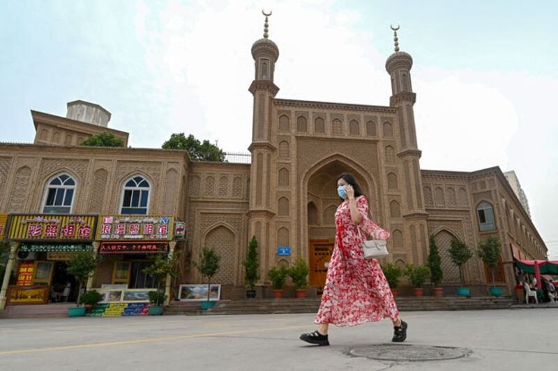 A Uyghur woman passes an old disused mosque in Artush, capital of Kizilsu Kyrgyz Autonomous Prefecture, in northwestern China's Xinjiang region, July 19, 2023. (Pedro Pardo/AFP)