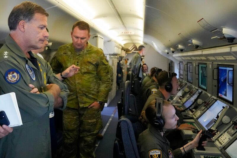 Admiral John C. Aquilino, left, commander of the U.S. Indo-Pacific Command, looks at videos of Chinese structures and buildings on board a US P-8A Poseidon reconaisance plane flying at the Spratlys group of islands in the South China Sea, March 20, 2022. Credit: AP