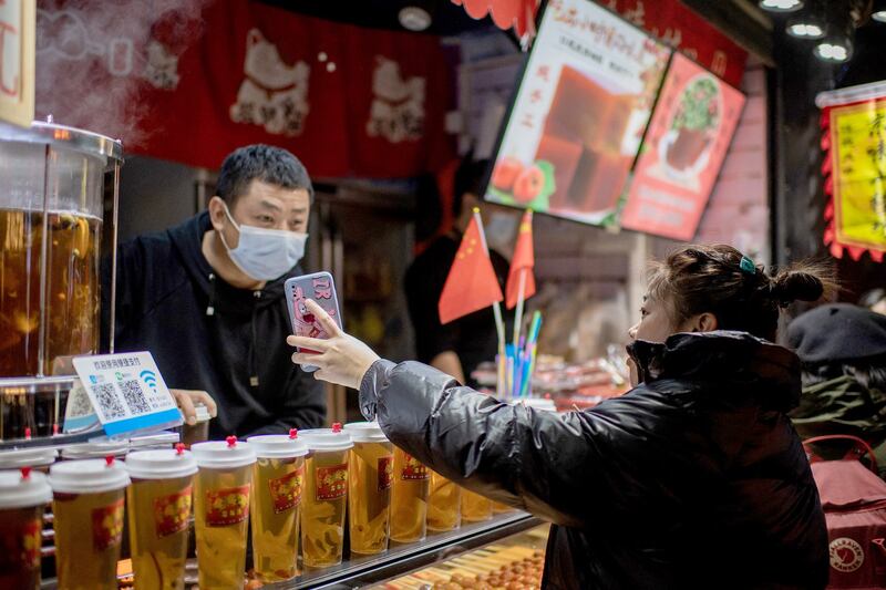 A customer shows her Alipay electronic payment confirmation to an employee at a beverage shop in Beijing in 2020. Some internet users have been confirming the authenticity of the stolen data using phone number and name searches via the Alipay system. Credit: AFP