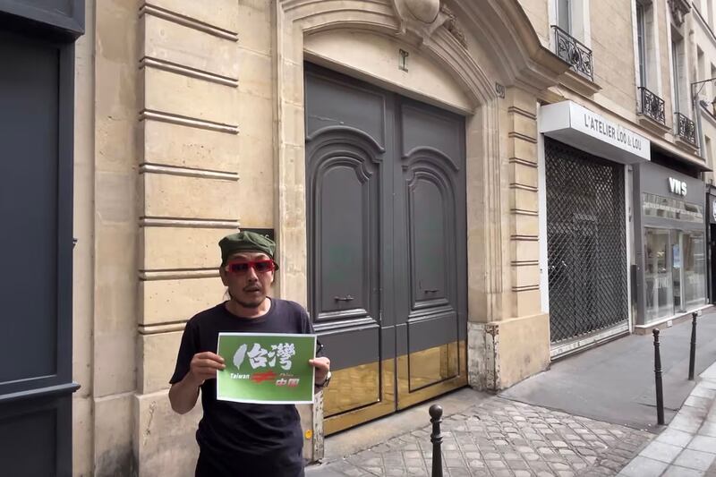 France-based citizen journalist Lin Linqi holds up a sign supporting democratic Taiwan outside the headquarters of the Peaceful Reunification Association of France, August 2024.