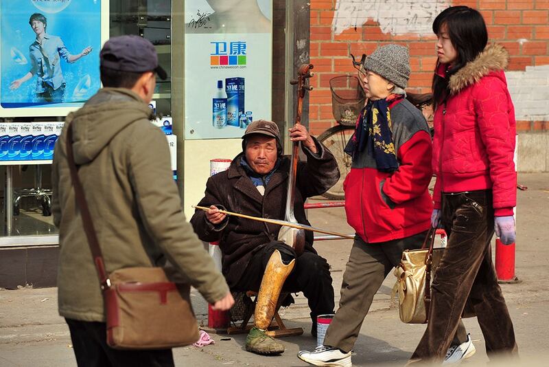 北京市一明残障人士在街头拉琴讨钱。(法新社资料图片)