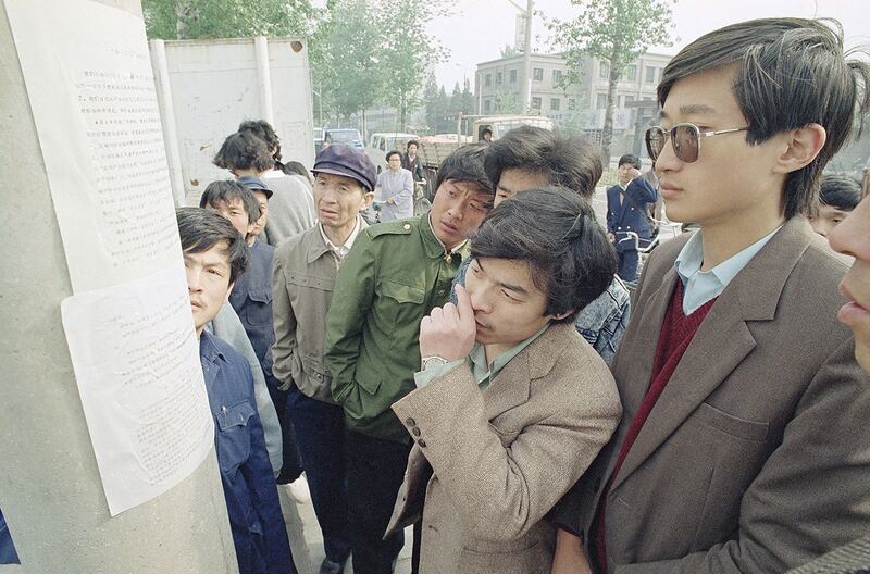 1989年4月24日，北京市民在北京大学附近的路灯杆上读学生印制的报纸，报道学生将罢课示威。（美联社）