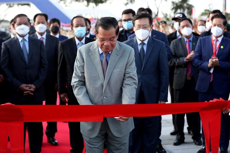 Cambodia's Prime Minister Hun Sen (C) cuts a ceremonial ribbon as Chinese ambassador to Cambodia Wang Wentian (3rd R) looks on during the opening ceremony of the Morodok Techo National Stadium, funded by China's grant aid under its Belt and Road Initiative, in Phnom Penh, Dec. 18, 2021. Credit: AFP