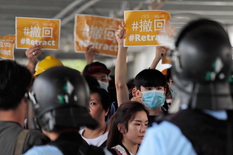 2019年6月13日，100多名示威者在香港立法会对面的行人桥聚集，部分人戴上口罩和头盔，他们展示标语并呼喊口号，要求政府撤回《逃犯条例》修订。（路透社）