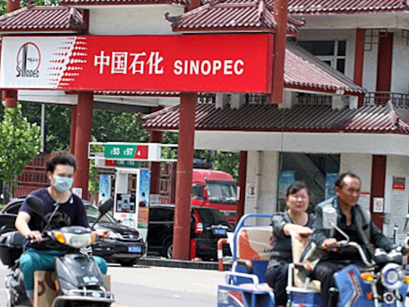 Chinese commuters ride past a Sinopec gas station in Xuchang, central China's Henan province, May 22, 2016.