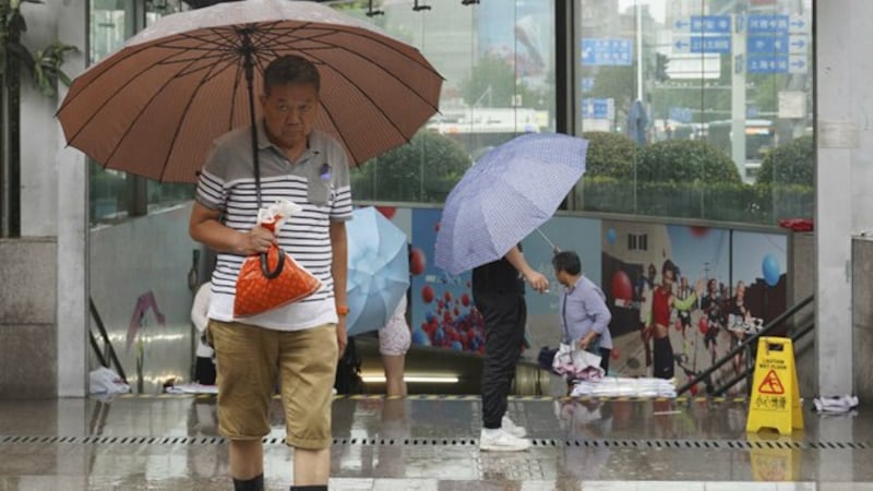 中国南方连续降雨，图为上海居民在雨中出行。（美联社）