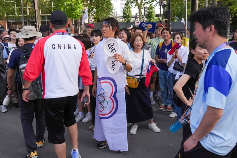 Members of Team China walk past fans of Taiwan who gathered outside Porte de la Chapelle Stadium, the venue for badminton, after Taiwan's Lee Yang and Wang Chi-lin defeated China's Liang Weikeng and Wang Chang in their men's doubles gold medal match at the 2024 Summer Olympics, Aug. 4, 2024, in Paris, France. (Dita Alangkara/AP)