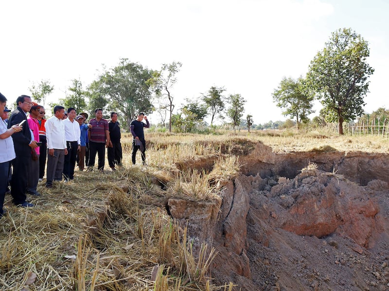 Khammouane Province Governor Vanxay Phongsavanh, left, and his delegation inspect a sinkhole in Pakpeng village, Laos, Dec. 4, 2024.