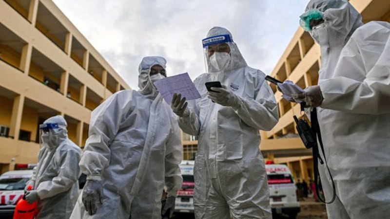 Volunteers wearing personal protective equipment check a list of individuals suspected of having the COVID-19 virus at a quarantine center in Myanmar's commercial city Yangon, Oct. 1, 2020.