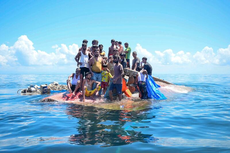 Rohingya refugees stand on their capsized boat before being rescued in the waters off West Aceh, Indonesia, March 21, 2024. (Reza Saifullah/AP)