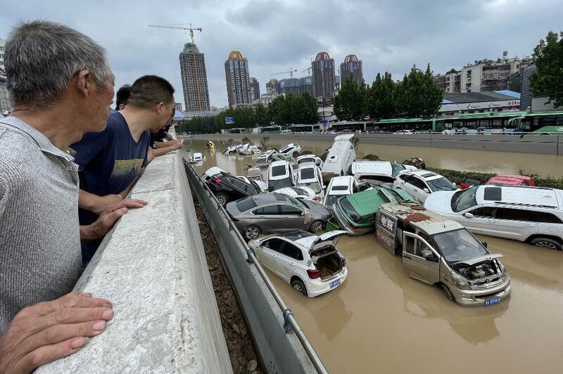 People look out at cars sitting in floodwaters after heavy rains hit the city of Zhengzhou in China's central Henan province, July 21, 2021. Credit AFP