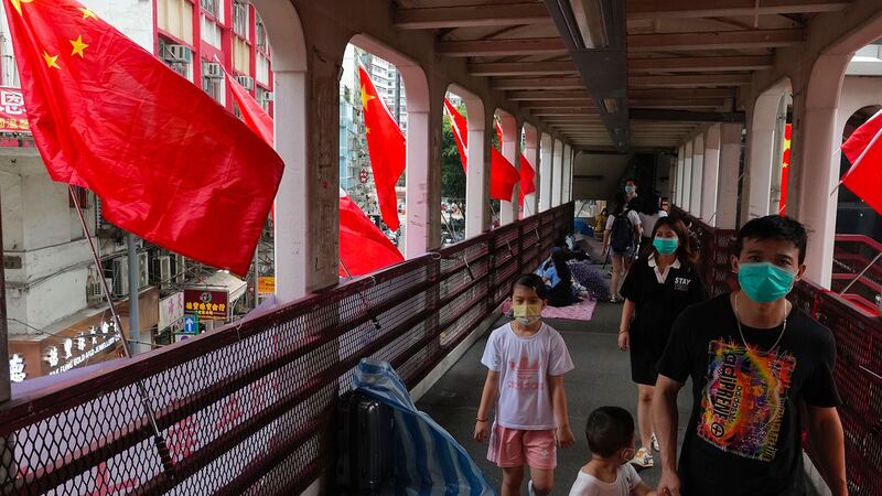 2021 年 7 月 1 日，香港主权移交24周年，居民走过在人行天桥上竖立的中国国旗。 （美联社）