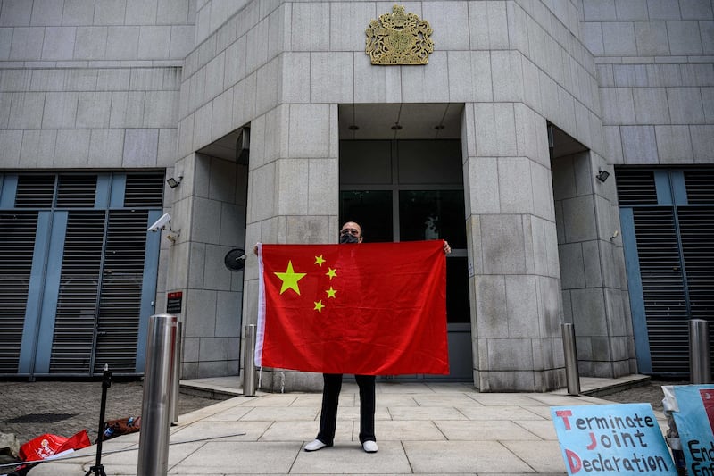 An activist holds the national flag of China after a pro-Beijing group gathered outside the British Consulate-General in Hong Kong to protest against the use of the British National (Overseas) passport on Feb. 1, 2021. Credit: Anthony Wallace/AFP