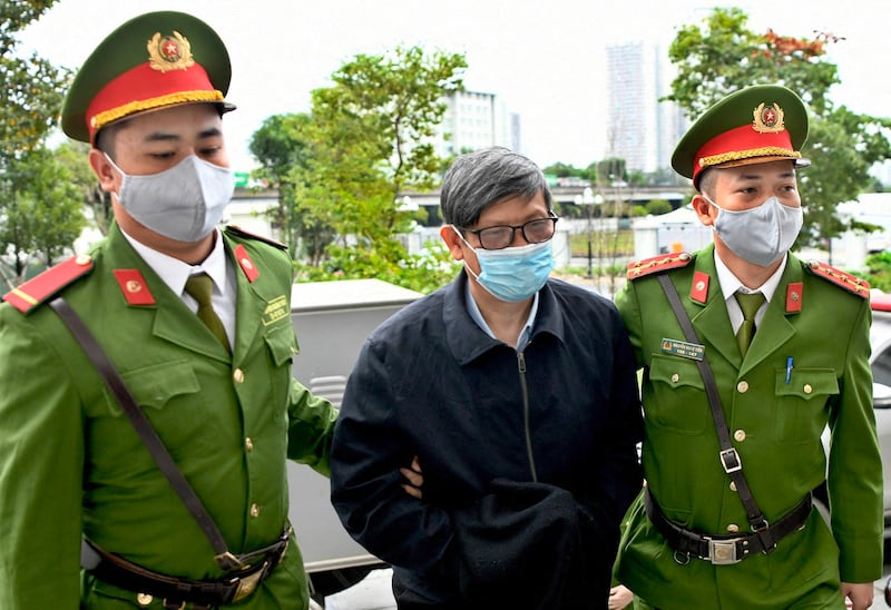 Vietnam's former minister of health Nguyen Thanh Long is led to a court by police officers to face an anti-corruption trial in Hanoi, Jan. 3, 2024. (Nhu Y/AFP)