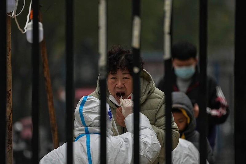 A woman has her routine COVID-19 test at a coronavirus testing site setup inside a residential compound in Beijing, Nov. 24, 2022. "A lot of money was wasted" with zero-COVID, says a resident of Jianjun. Credit: Associated Press