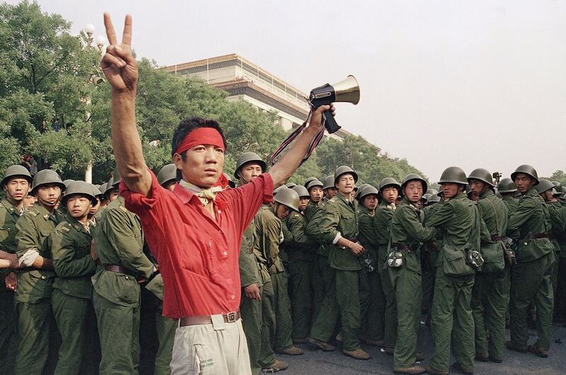 1989年6月3日，北京，一名学生在人民大会堂西侧向人群比出胜利手势，随着解放军的撤退。（美联社）