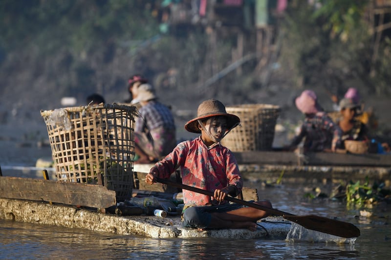 A young waste collector paddles a polystyrene boat looking for plastic and glass to sell in Pazundaung Creek in Yangon, Myanmar, Jan. 14, 2023. Dozens of Myanmar citizens are taking to the murky creek waters after being unable to find work amid the post-coup economic crisis. Credit: AFP