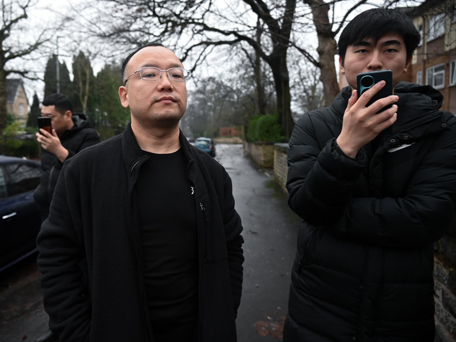 A staff member from the Chinese consulate in Manchester, center, tells an RFA reporter they can't take photos on the street outside the building, Dec. 28, 2024.