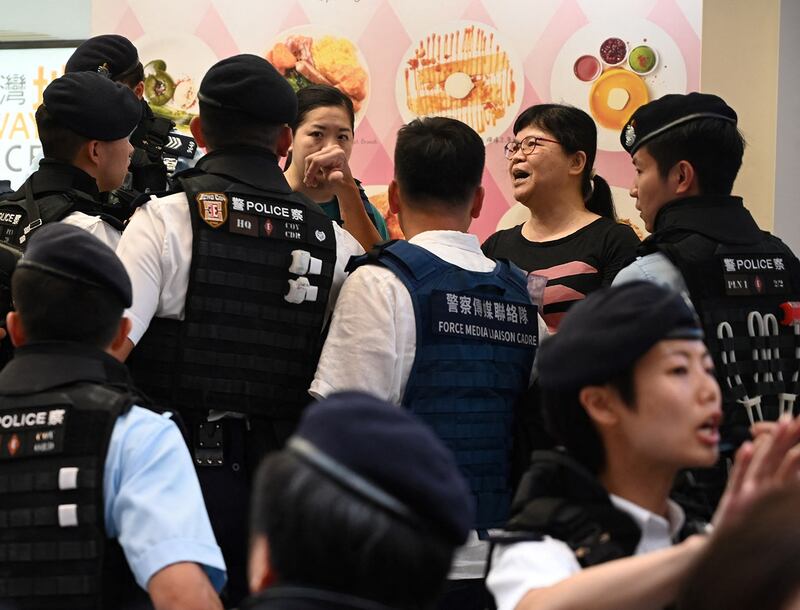 Former Hong Kong Journalist Association President Mak Yin-ting, top right, is questioned by police before being taken away in the Causeway Bay shopping district of Hong Kong on June 4, 2023 (Peter Parks/AFP)