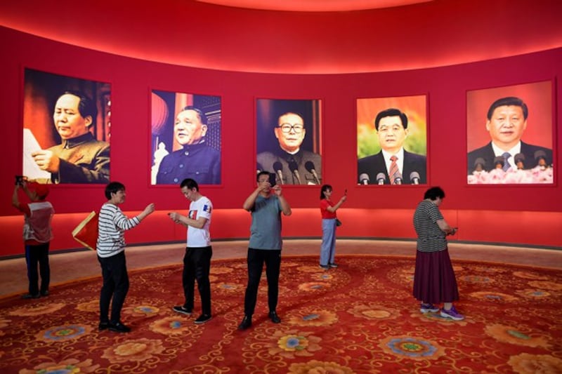 People take pictures in front of portraits of, from left, the late Chinese chairman Mao Zedong and former Chinese leaders Deng Xiaoping, Jiang Zemin, Hu Jintao and current president Xi Jinping at an exhibition in Beijing, Sept. 26, 2019. (Wang Zhao/AFP)